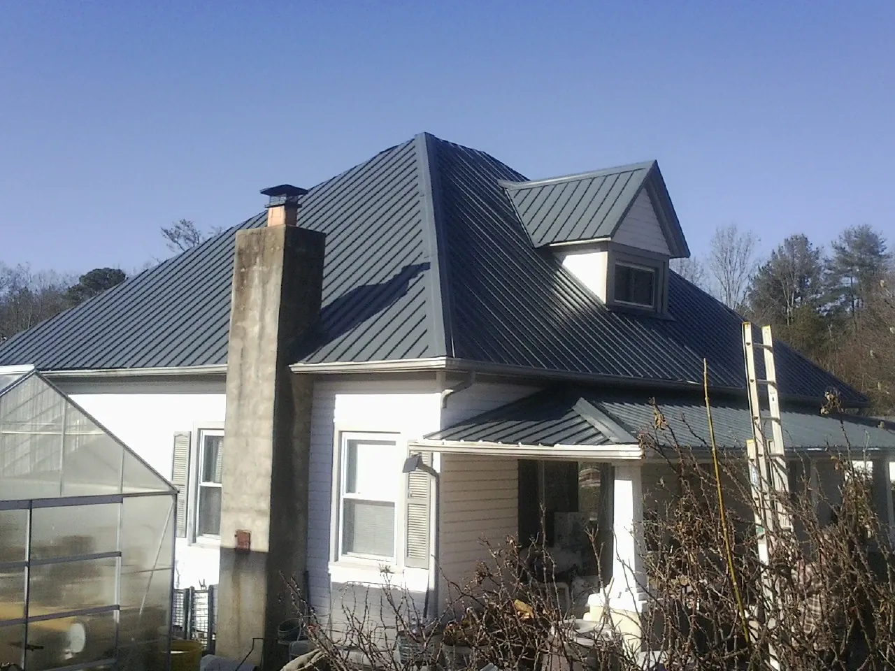 Dark blue standing seam metal roof on a white farmhouse with dormer — Slate & Tile Roof Repair by Roofing Brothers in Mount Victory