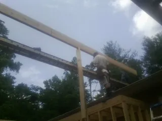 Carpenter setting a ridge beam over a new addition frame — Ice Dam Removal by Roofing Brothers in Mount Victory
