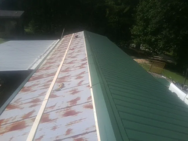 Old rusted panels beside newly installed green metal roofing — Wind Damage Roof Repair by Roofing Brothers in Mount Victory