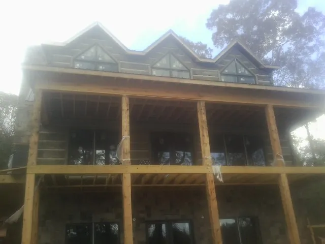 Dormers and porch framing on a large log home under construction — Roof Coating work by our crew in Mount Victory