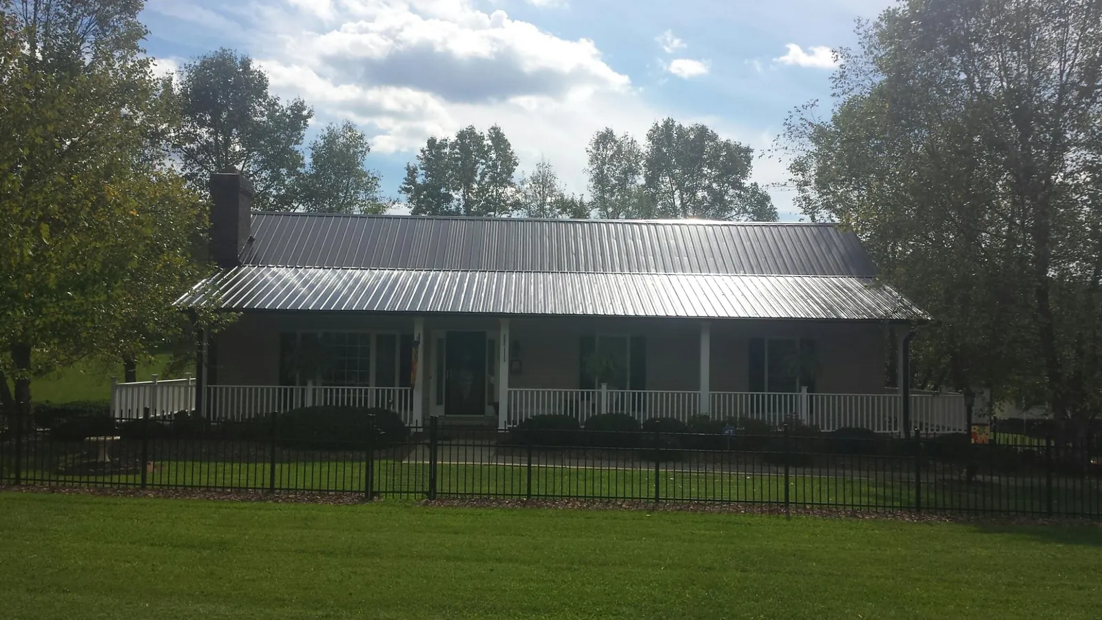 Gray metal roof on a brick ranch with a full width front porch — Gutter Guard Installation work by our crew in Mount Victory
