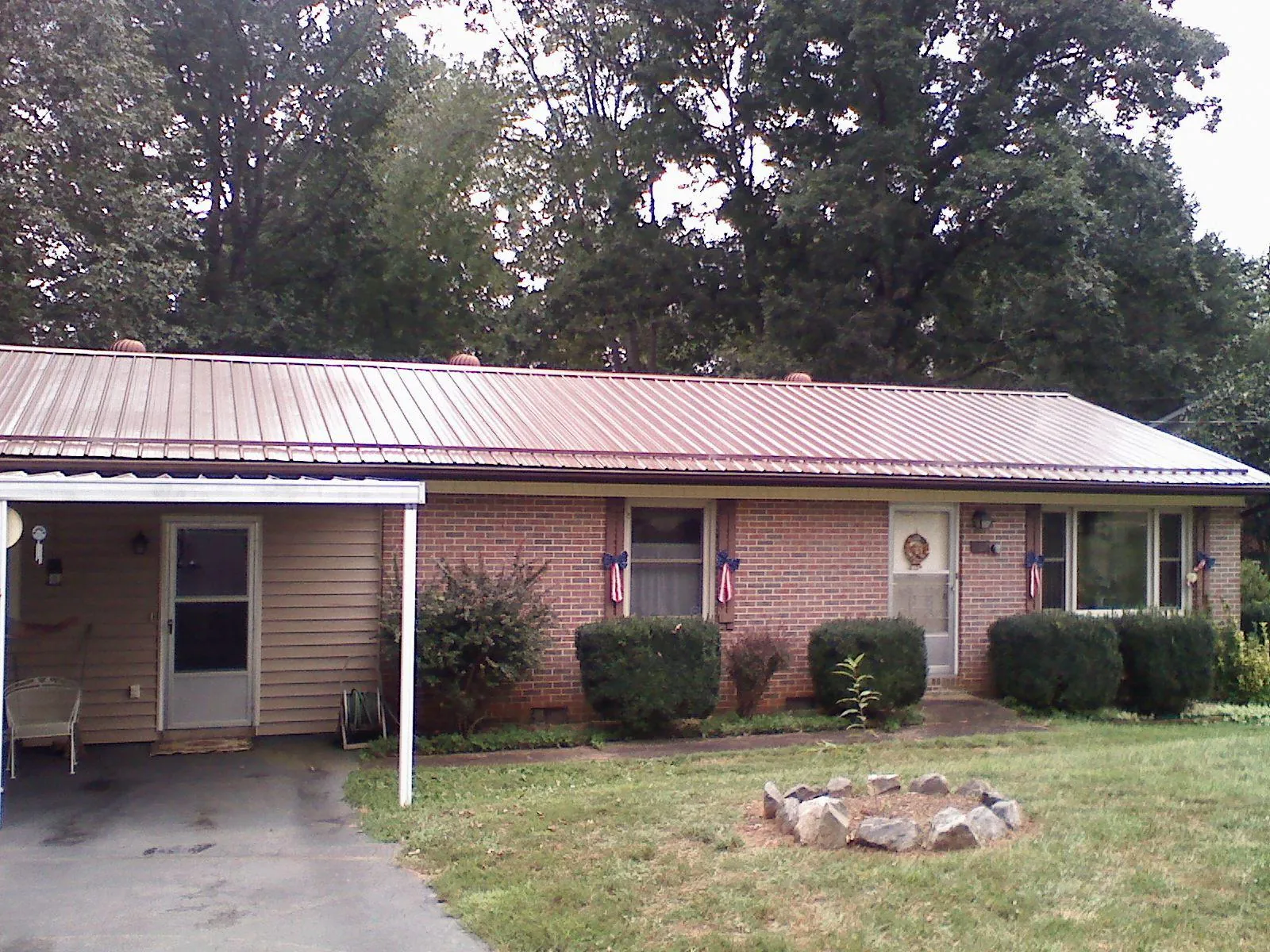 Bronze metal roof and carport on a brick ranch home — Roof Repair work by our crew in Mount Victory