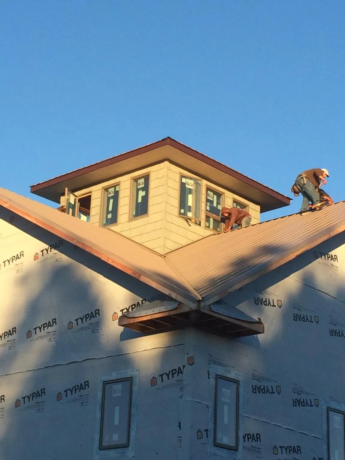 Roofers working around a rooftop cupola on a new metal roof at sunset — Roof Waterproofing in Mount Victory by Roofing Brothers